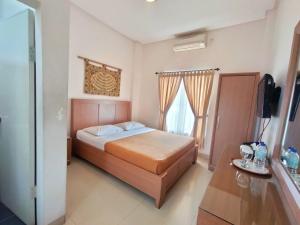 巴东The Sriwijaya Hotel - Halal Hotel的一间卧室配有一张床和一台电视