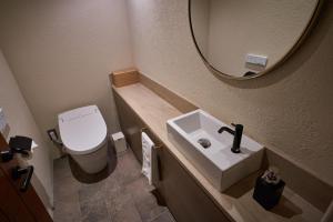 松山Hotel Lepo Chahal的一间带卫生间、水槽和镜子的浴室