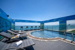 岘港Nguyen Gia Hotel的一个带椅子的游泳池的酒店,享有海景