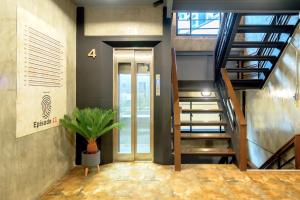 曼谷OYO 75456 Episode 11 Hostel Sukhumvit的走廊上设有楼梯和盆栽植物