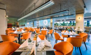 比克Hunguest Bük - ex Répce és Répce Gold的一间设有橙色椅子和桌子的餐厅