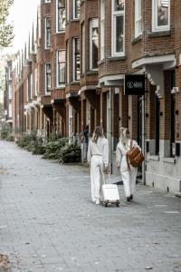 鹿特丹Le Petit Marin Boutique Hotel的两个女人在街上拉着一个手提箱