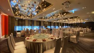 桃园市尊爵大饭店的宴会厅配有白色的桌椅和吊灯