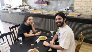 伯利恒Hikaya Collective Hostel的坐在餐桌上吃一盘食物的男人和女人