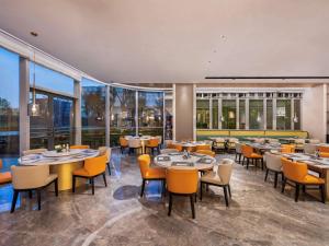 上海上海万源诺富特酒店的餐厅设有桌椅和大窗户。