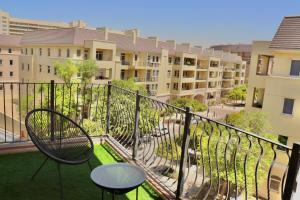迪拜Unified Vacation Homes-Spacious Studio in lush green Motor City的一个带桌椅的公寓阳台