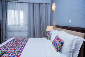 利伯维尔Hotel Hibiscus Blvd Triomphal的卧室配有带枕头的白色床和窗户。