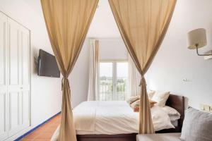 埃尔罗西奥GINVA - Apartahotel El Rocio-Doñana的一间卧室配有一张天蓬床和窗户