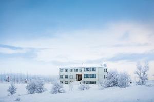 塞尔福斯Ljosafoss Guest House的雪中白色的建筑,有雪覆盖的树木
