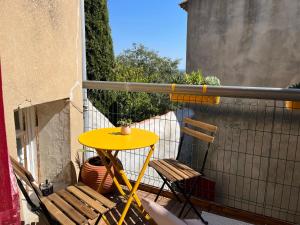 Châteauneuf-de-GadagneAtypique的阳台配有一张黄色桌子和两把椅子