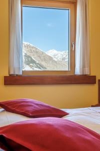 利维尼奥Hotel San Rocco的窗前带红色枕头的床