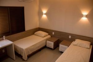 Chapadão do SulRosa Vilma Hotel的一间卧室配有两张床,墙上有两盏灯