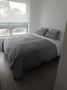 埃斯特角城Apto en Punta del Este con Piscina Climatizada!!的卧室内的一张带黑白条纹棉被的床