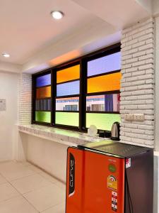 芭东海滩Baankasemsuk Resort 般咔 深宿的带2扇窗户和橙色冰箱的厨房