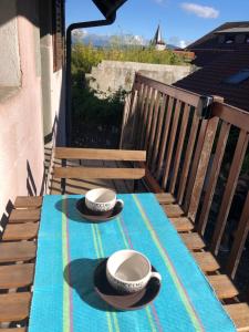 安锡Appartement dans la vieille ville, en face du château的阳台上的桌子上放着两顶帽子和杯子