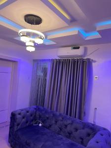 拉各斯GS HOMES的带沙发的客厅以及带紫色灯的天花板