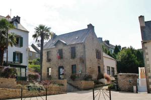 LocquénoléLocquenole house with sea view的一座古老的石头建筑,后面有棕榈树