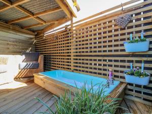 基里缪尔Lindsay Cottage的木甲板上的热水浴池,种植了两盆植物