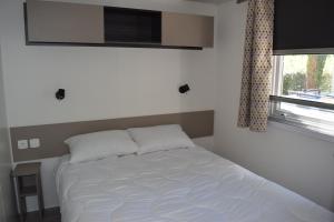 加斯泰Mobilhome 526 3ch/2SDB camping 4* La Réserve SIBLU Gastes的卧室内的一张白色床,设有窗户