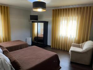 巴塞卢什Residencial Solar da Estação的酒店客房带两张床、椅子和镜子