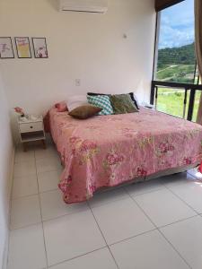 蒙蒂达斯加梅莱拉斯Lá na Roça - Belezas do Monte Chalé, Suítes & Restaurante的一间卧室配有一张带粉色毯子的床和窗户。