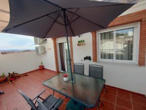 拉苏维亚Ático Granada al Sol (terraza vistas montaña)的庭院内桌椅和遮阳伞