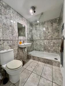 伦敦Great 2 bedrooms apartment 15 mins from the centre的浴室配有卫生间、浴缸和水槽。