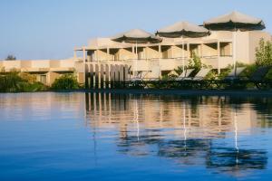 埃亚玛琳娜奈奇多Giannoulis – Santa Marina Beach Hotel的水体旁的一座带椅子和遮阳伞的建筑