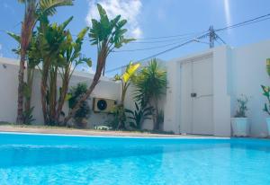 突尼斯Maison plain-pied avec piscine chauffée的一座树木繁茂的房屋前的游泳池