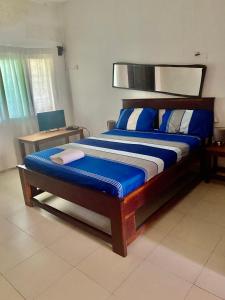 科洛里Queen Zee Garden Apartments的一间卧室配有一张带蓝白色床单的大床