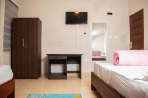 AfwerasiEl-King Home Lodge的一间卧室配有两张床和一张书桌及电视