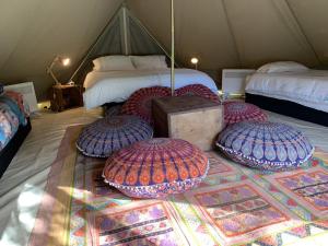 CoodanupLuxury 6 metre Bell Tent & Outdoor Bathroom, WIFI, TV and firepit,的客房内的地毯上带四个枕头的帐篷