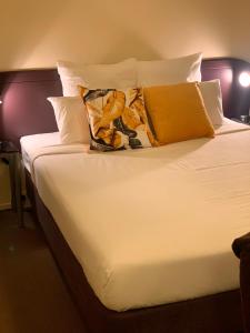 北帕默斯顿B-Ks Premier Motel Palmerston North的一张配有白色床单和黄色枕头的大床