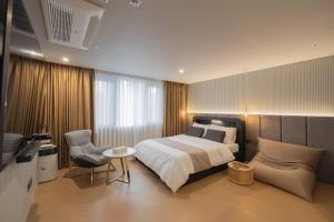 釜山동래 덴바스타 호텔的一间卧室配有一张床、一把椅子和电视