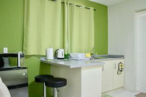 威廉斯塔德Eve's Residence的厨房设有绿色的墙壁和带凳子的台面