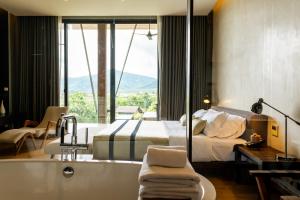 慕斯Atta Lakeside Resort Suite - SHA Plus Certified的卧室配有床、浴缸和窗户。