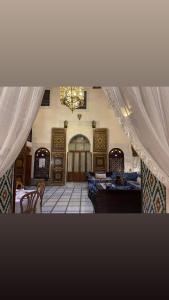 梅克内斯Riad Dar AlKATIB Meknès的配有窗帘和桌子以及吊灯的房间