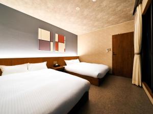 那霸Rakuten STAY Naha-Miebashi Suite Room的配有两张床的酒店客房中的两张床