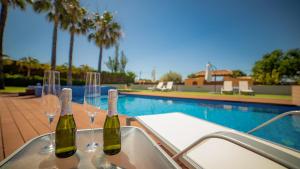 布索特Hotel Boutique Canelobre的游泳池旁桌子上放上两瓶葡萄酒和玻璃杯