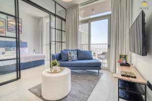 迪拜Lovely 1 Bedroom Apartment in Collective 2.0的客厅配有蓝色的沙发和床。