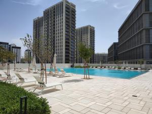 迪拜Lovely 1 Bedroom Apartment in Collective 2.0的一座带躺椅的游泳池以及建筑