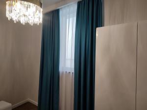 乌日霍罗德Nicole的客房设有带蓝色窗帘和吊灯的窗户。