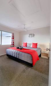 派西亚Paihia Apartments的一间卧室配有一张带红色枕头的大床