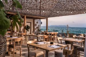古瓦伊Enorme Maya Beach Hotel-Adults Only的海滩上的餐厅,配有桌椅