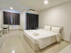 曼谷Donmueang Place Hotel - SHA Plus的卧室配有一张白色大床和一张书桌
