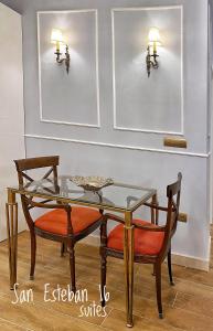 塞维利亚SUITES SAN ESTEBAN 16 Real的一间设有玻璃桌和两把椅子的用餐室