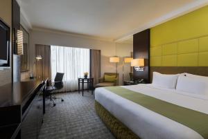 新加坡Holiday Inn Singapore Orchard City Centre, an IHG Hotel的酒店客房设有一张大床和一张书桌。