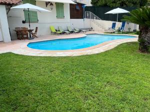 尼斯Villa Paradiso, logement avec piscine, Nice Nord的庭院内的游泳池,配有椅子和桌子