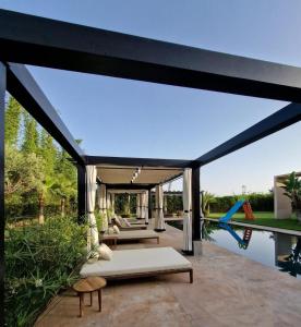 马拉喀什Villa Le Clos de l'Atlas的一个带游泳池和大型玻璃延伸区的户外庭院