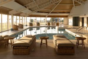 奈恩克瑞拉高尔夫景酒店&SPA的一座带藤椅和桌子的游泳池,位于一座建筑中
